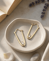 Gold plated moonstone drop earrings displayed on a vanity, showing iridescent blue-white gemstones with delicate gold hardware