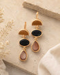 Gold-plated triple stone cat eye drop earrings on stone surface, flat lay showing amber, black, and blush stone set