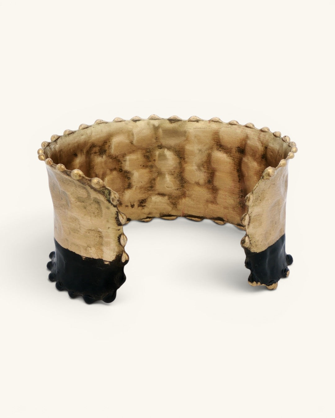 Hand-hammered brass cuff bracelet with black band, interior view showing unfinished brass inner surface and beaded trim detail