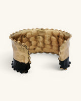 Hand-hammered brass cuff bracelet with black band, interior view showing unfinished brass inner surface and beaded trim detail