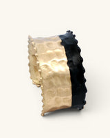 Hand-hammered brass cuff bracelet with black band, side profile view showing full height of gold and black two-tone design