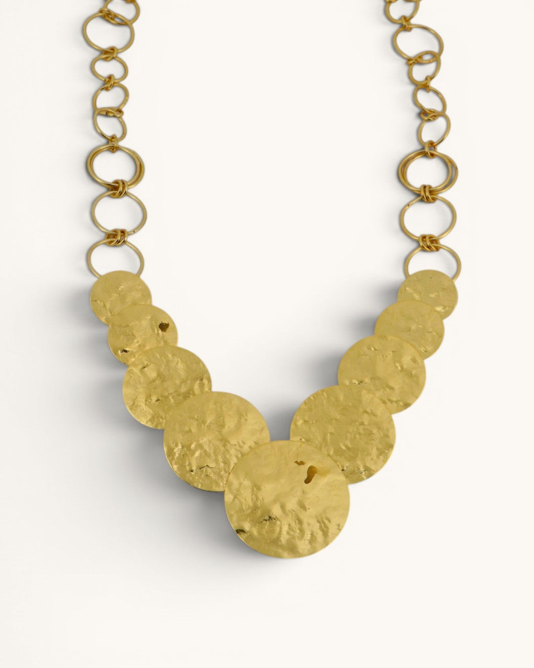 Hammered brass cascading disc necklace close-up of graduated discs and open ring chain, cropped front detail view