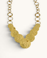 Hammered brass cascading disc necklace close-up of graduated discs and open ring chain, cropped front detail view