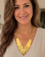 Hammered brass cascading disc necklace worn by a model in a white top, showing fit and drape at the neckline