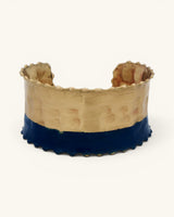 Hand-hammered brass cuff bracelet with indigo painted lower band and scalloped beaded edges, front view on white background