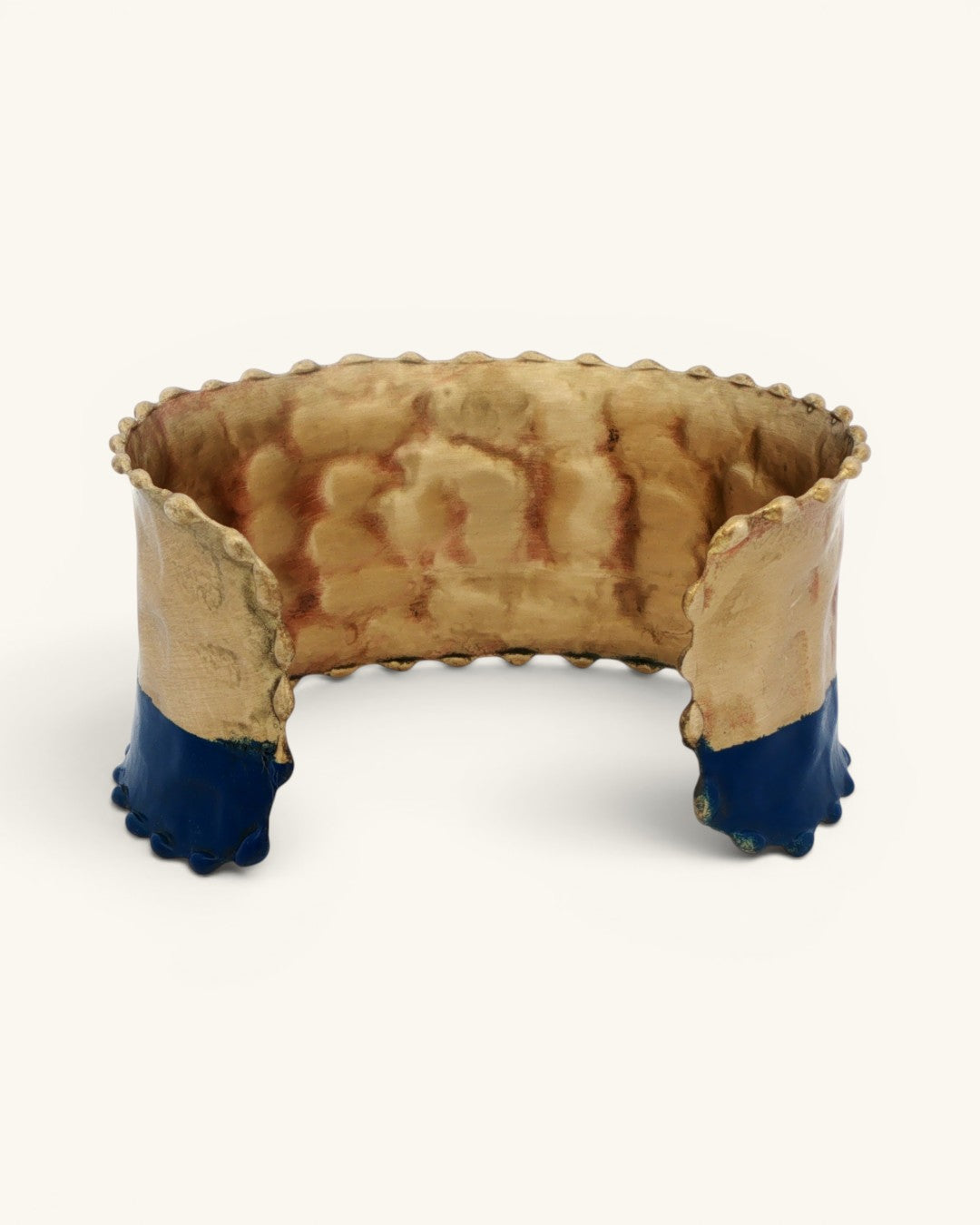 Hand-hammered brass cuff bracelet interior view showing raw hammered brass surface, beaded top edge, and indigo painted lower cuff ends