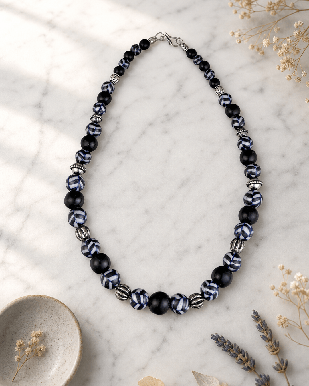 Hand-Painted Black Ceramic Pottery Bead Necklace with Metal Accents — necklaces, editorial marble lifestyle photo
