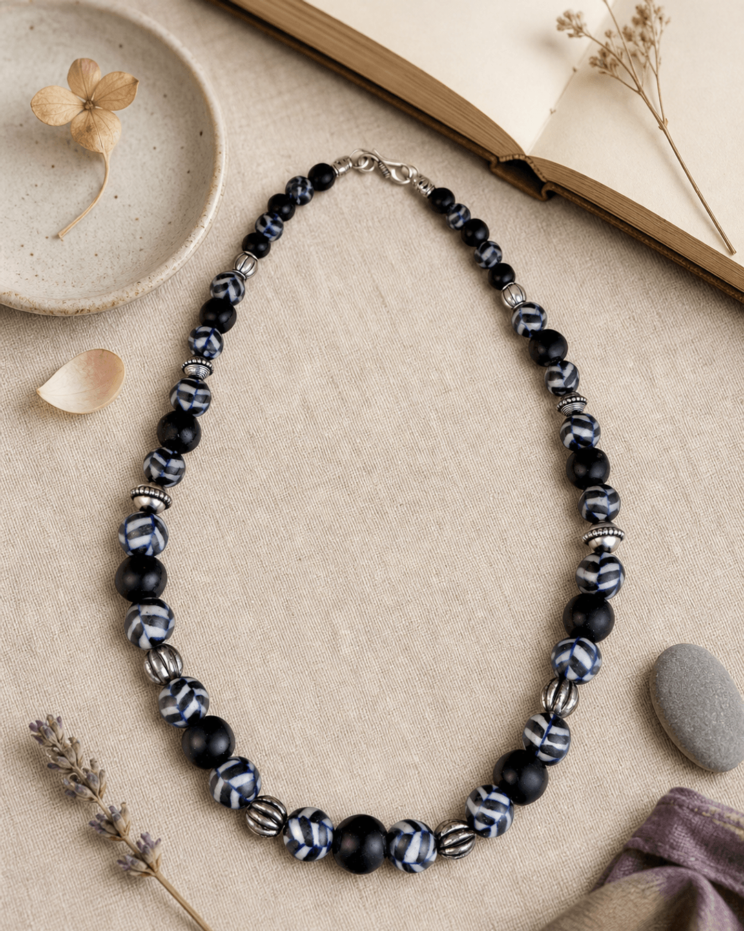 Hand-Painted Black Ceramic Pottery Bead Necklace with Metal Accents — necklaces, flatlay linen lifestyle photo
