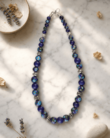 Hand-Painted Blue Pottery Bead Necklace with Floral Patterns — necklaces, editorial marble lifestyle photo