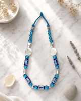 Hand-Painted Blue Pottery Bead Necklace with Metal Accents — necklaces, editorial marble lifestyle photo