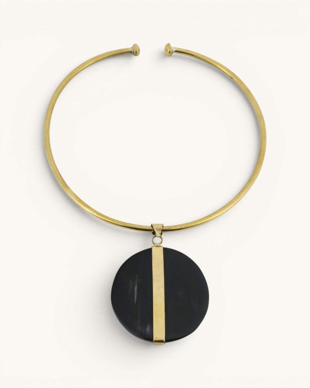 Horn and brass disc choker necklace front view, round black horn pendant with vertical brass bar on gold open collar