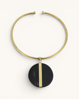 Horn and brass disc choker necklace front view, round black horn pendant with vertical brass bar on gold open collar