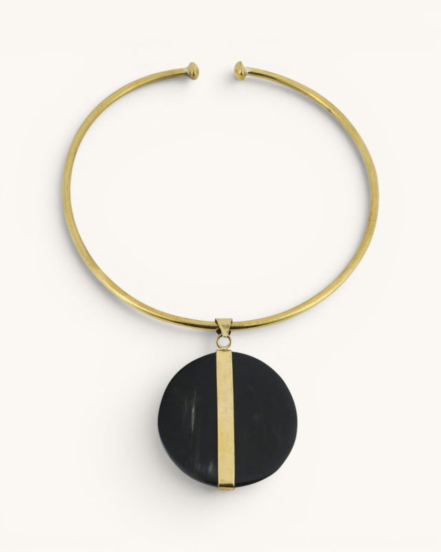Horn and brass disc choker necklace front view, round black horn pendant with vertical brass bar on gold open collar