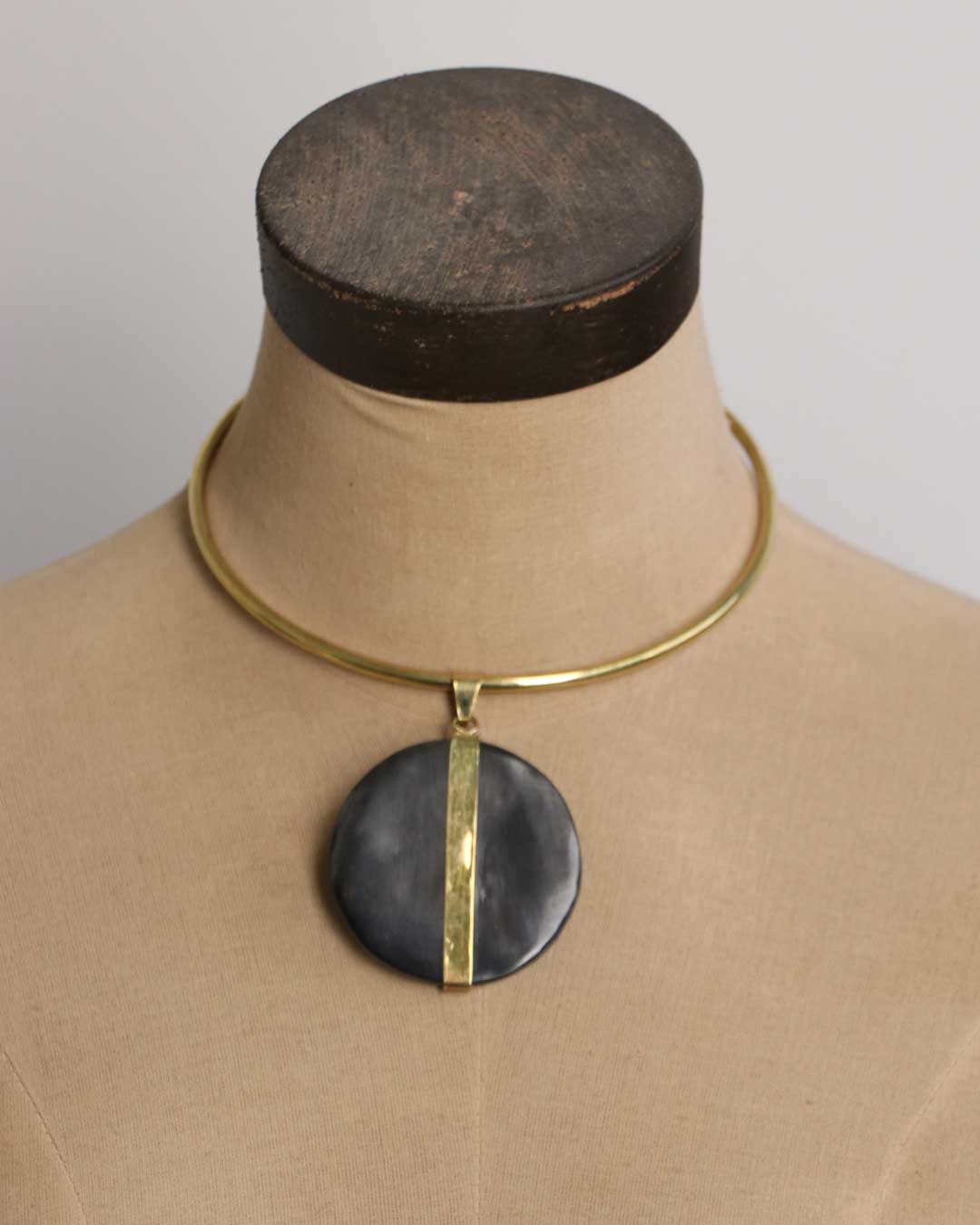 Horn and brass disc choker necklace on fabric dress form showing open brass collar and large round black horn disc pendant