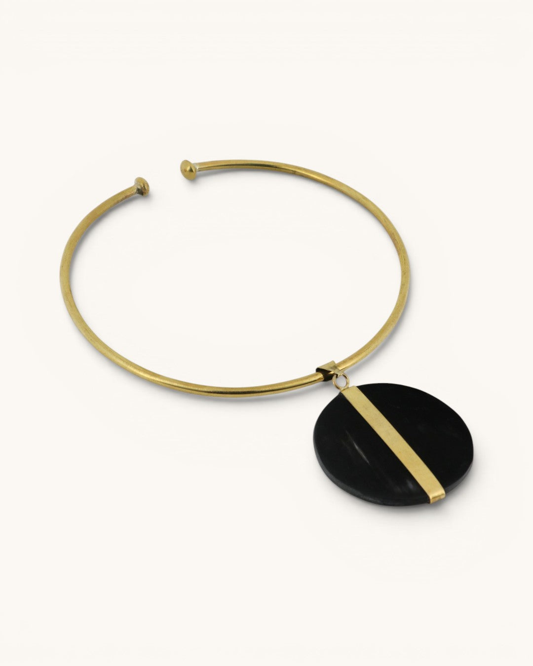 Horn and brass disc choker necklace angled on white background, showing open collar ends and black horn disc with brass bar detail