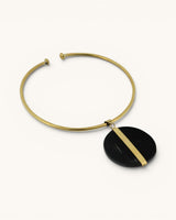 Horn and brass disc choker necklace angled on white background, showing open collar ends and black horn disc with brass bar detail