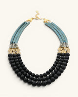 Jet glass and hematite triple strand necklace slight angle view on white, showing matte black bead layers and teal herringbone strands
