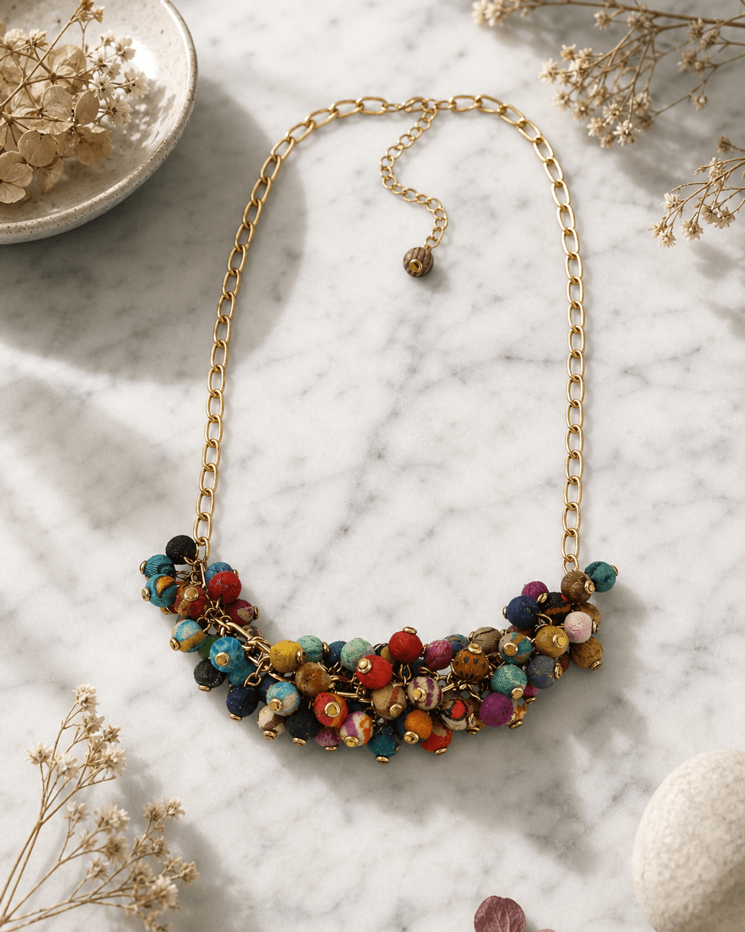 Kantha beaded cluster necklace styled as a convertible choker on a white marble surface