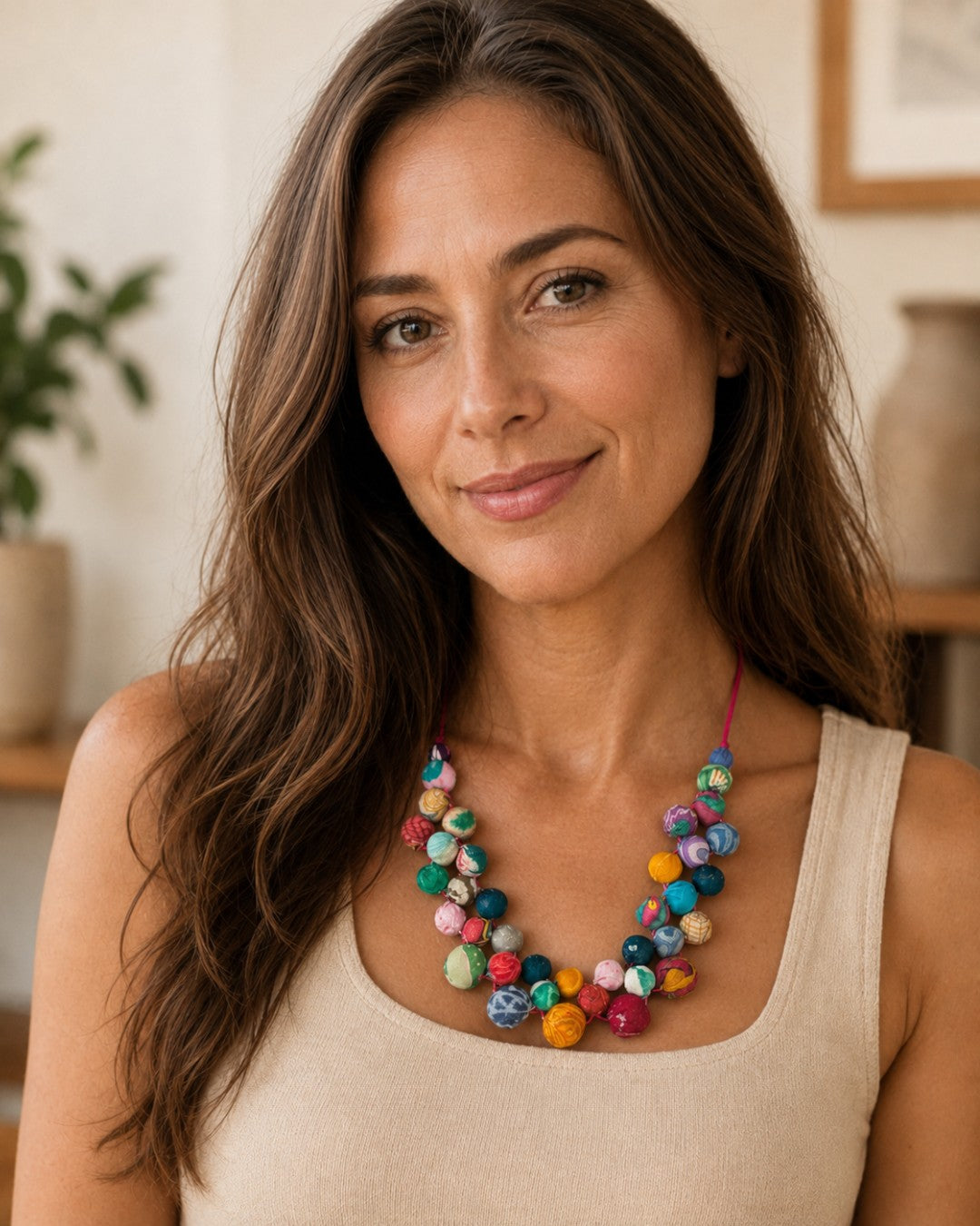 Kantha recycled textile layered bead necklace worn by a woman in a cream tank top, two rows of multicolor fabric beads at neckline