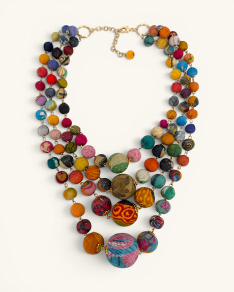 Kantha recycled textile four-strand statement necklace flat lay on white background, gold chain clasp visible at top