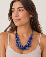 Kantha recycled sari textile bead layered necklace in indigo blue worn by a woman in a beige tank top, front view