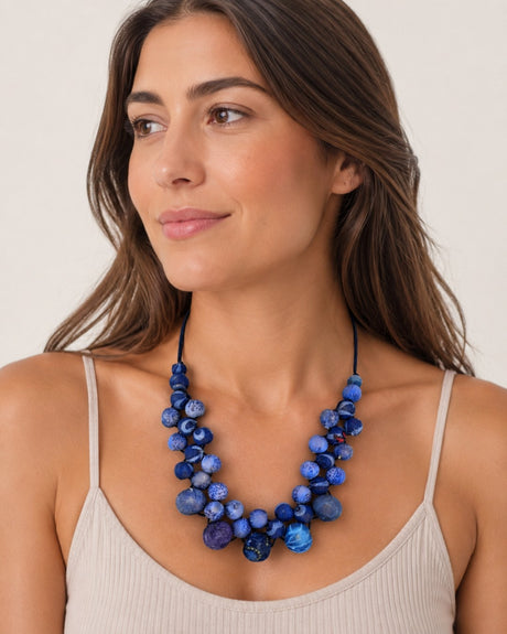 Kantha recycled sari textile bead layered necklace in indigo blue worn by a woman in a beige tank top, front view