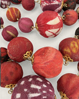 Close-up of kantha sari fabric-wrapped beads in red, maroon, and burgundy with mixed patterns and gold filigree connectors