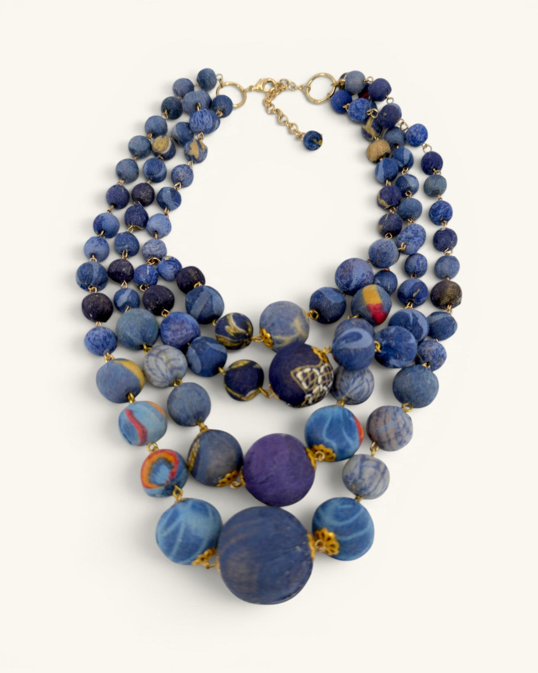 Blue kantha sari bead necklace with four strands, overhead flat-lay showing graduated bead sizes and gold wire links
