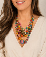 Kantha four-strand statement necklace worn by a model in a cream v-neck top, showing layered multicolor fabric beads