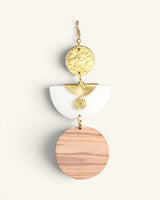 Single Kazuri brass and wood statement earring close-up on white background showing hammered disc, brass wire spiral connector, and round wood disc