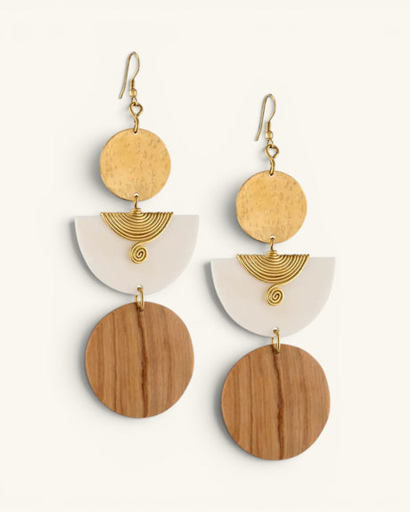 Kazuri brass and wood statement earrings shown as a pair, with hammered disc, white half-moon, and wood circle tiers on cream background