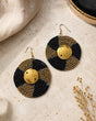 Kenyan hand-beaded circle earrings with alternating black and gold bead rows and engraved brass shilling center, styled product view