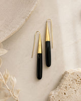 Kanai Kenyan hand-carved horn and brass threader earrings styled on marble surface with dried botanicals, front view