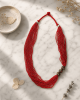 Multi-Strand Red Glass Bead Necklace with Hand-Painted Ceramic Accents — necklaces, editorial marble lifestyle photo