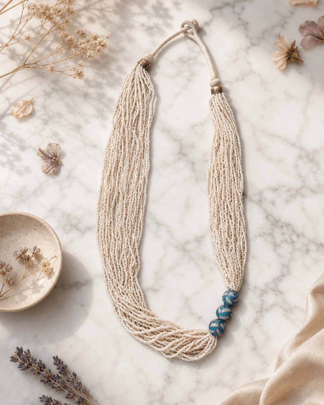 Multi-Strand White Glass Bead Necklace with Hand-Painted Ceramic Accents — necklaces, editorial marble lifestyle photo