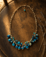Blue textile beaded necklace with vibrant rim lighting highlighting woven fabric beads and layered strand detail