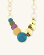 Hand-forged patina brass disc cascade necklace laid flat, showing cascading brass disc pendants arranged along a delicate chain
