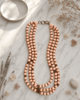 Peach-Pink Multi-Strand Wood Bead Necklace with Brass Accents — necklaces, editorial marble lifestyle photo