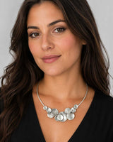 Silver-plated pewter collar necklace with stacked disc cluster worn by a brunette model in a black v-neck top