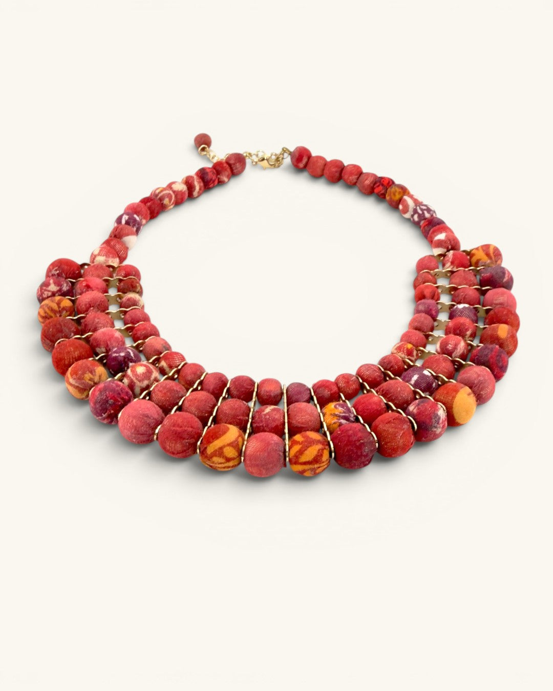 Red textile-wrapped bead layered bib necklace at an angle on white background, showing four-row bib depth and gold wire links