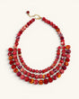 Red textile-wrapped bead layered bib necklace flat lay, four rows of mixed red beads with gold wire connectors and clasp