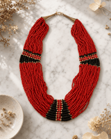 Red statement necklace with black beads displayed on white marble surface