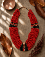 Red statement necklace with black beads on botanical flatlay with green leaves