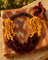 Handmade wooden disc pendant necklace with sunset flame twist design displayed on a sunlit outdoor window ledge with textile backdrop