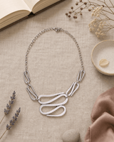 Swirly S-Shaped Statement Necklace — necklaces, flatlay linen lifestyle photo
