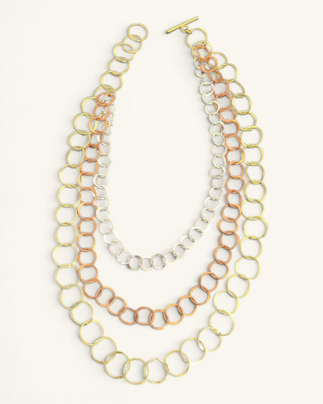 Three-strand mixed metal chain necklace laid flat on white background with all three circle-link strands and toggle bar clasp visible
