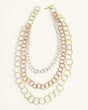 Three-strand mixed metal chain necklace laid flat on white background with all three circle-link strands and toggle bar clasp visible