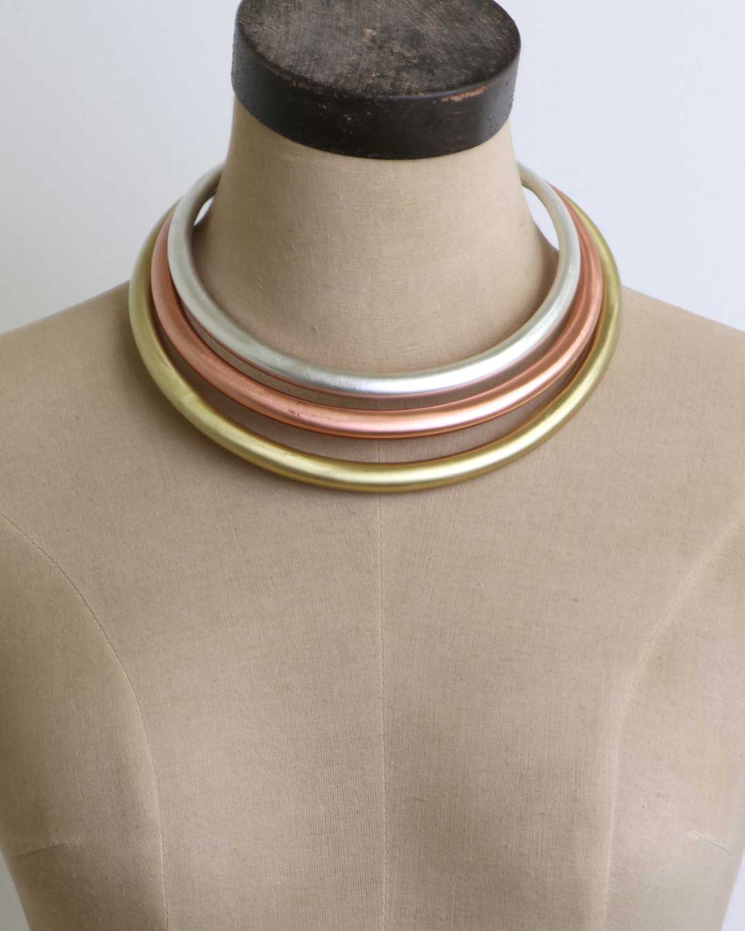 Tri-Tone Brass Collar Necklace on a beige dress form mannequin showing three concentric silver, copper, and brass bands at the neck