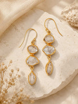 Triple Herkimer quartz gold-plated drop earrings laid on a stone surface with dried flowers, styled lifestyle view
