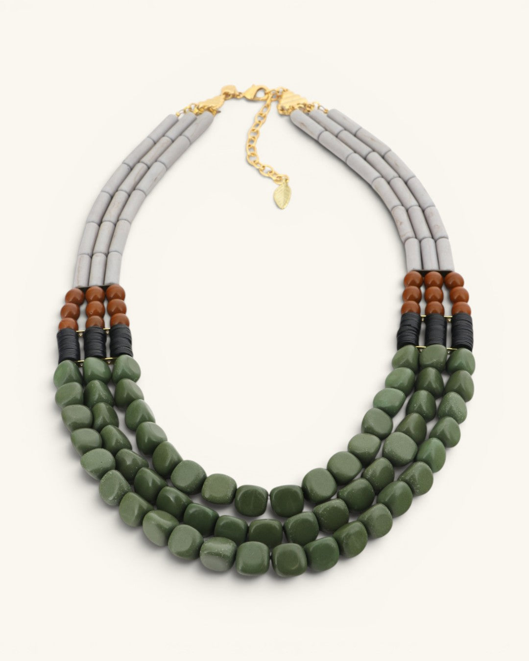 Triple strand magnesite, serpentine and vulcanite beaded necklace with gold lobster clasp, angled front view on white background